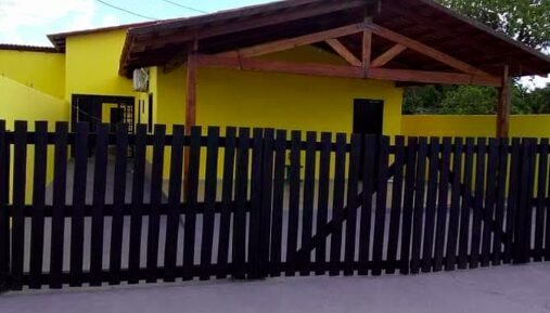 Fachada de casa amarela com cerca preta